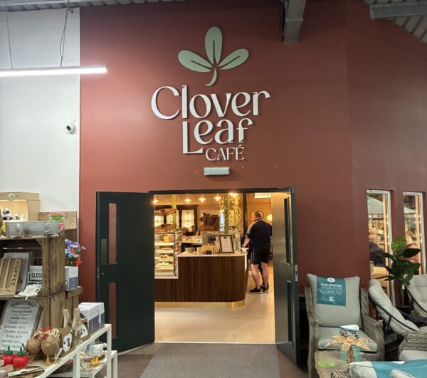 Clover Leaf Café entrance at Chacewater Garden Centre with pastry counter, coffee bar, homeware shelves and wicker seating.